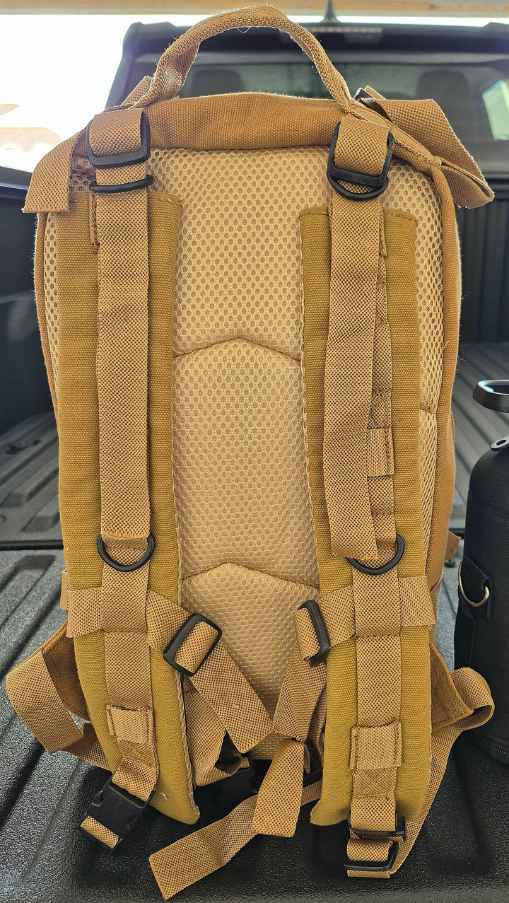 GS-007 Tan Tactical Pack shown on textured truck bed, highlighting padded shoulder straps, side compression straps, and rugged canvas build; positioned in field-ready staging context to suggest utility during transport, deployment, or outdoor operations